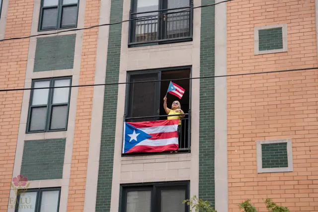 A Puerto Rican flag hanging from an open apartment window.