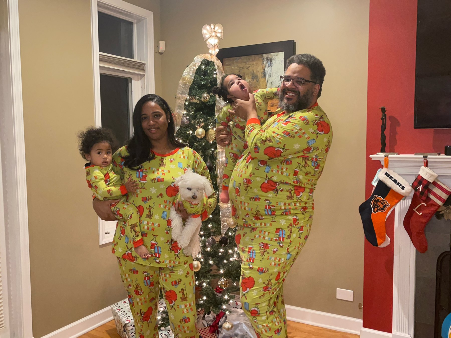 Falú lifting Havana, Indira holding her brother Luca and the family dog, everyone in matching Christmas pajamas by the tree.
